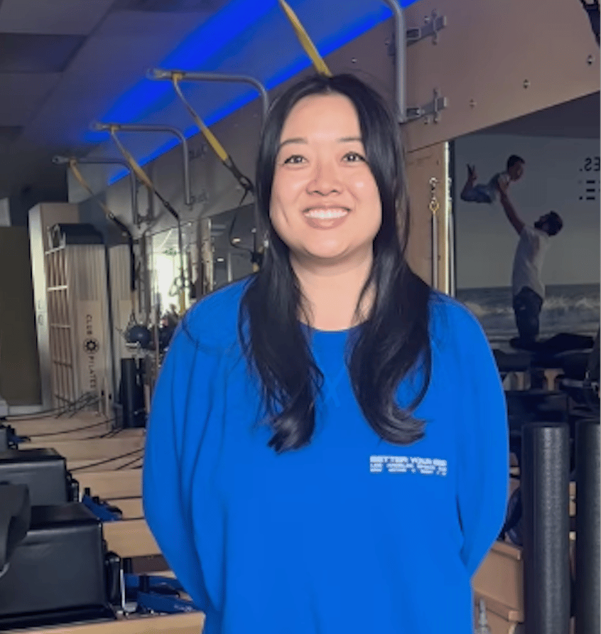 Smiling member at Club Pilates studio in blue sweatshirt