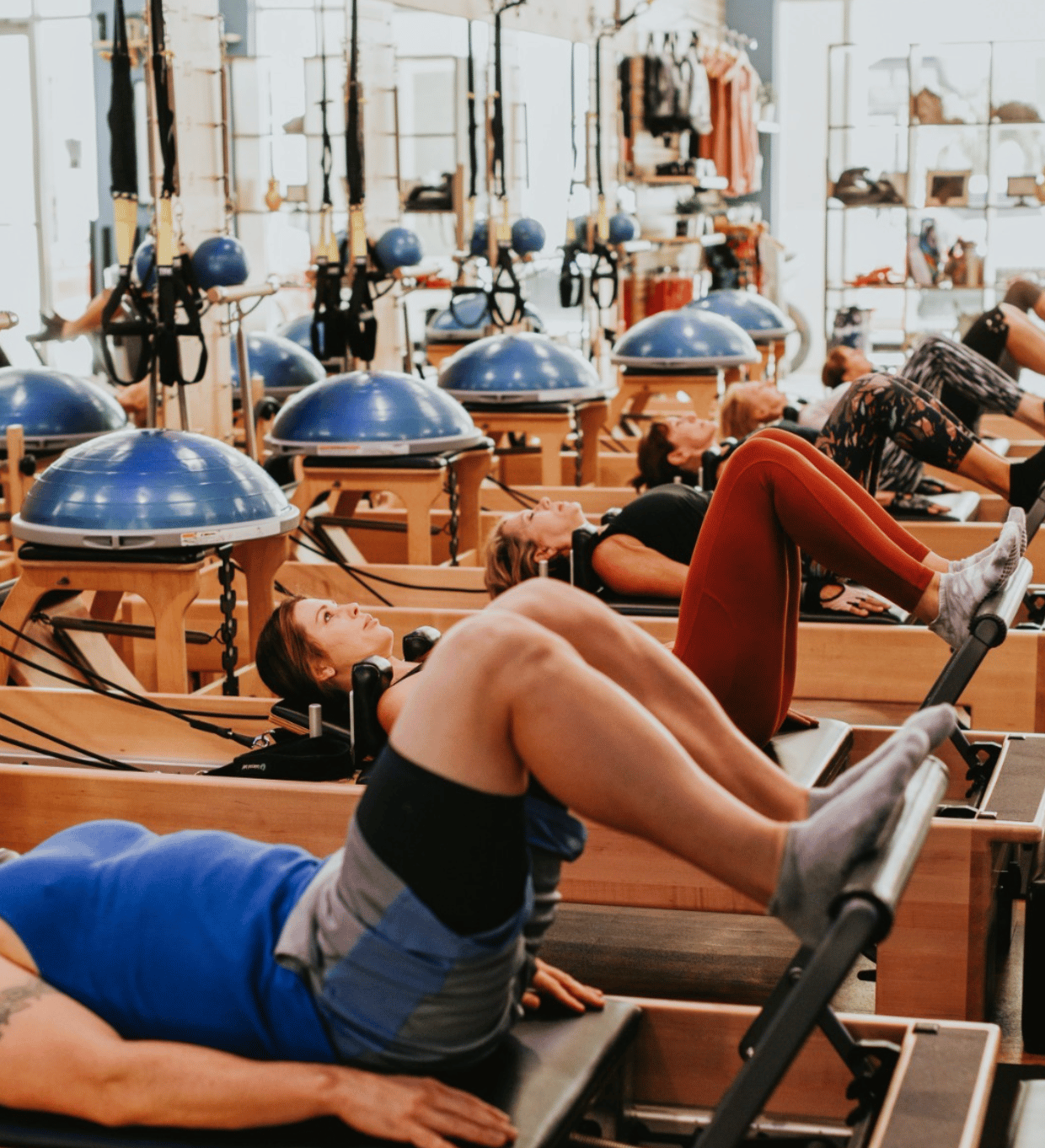 Middle aged men and women in Reformer Pilates class